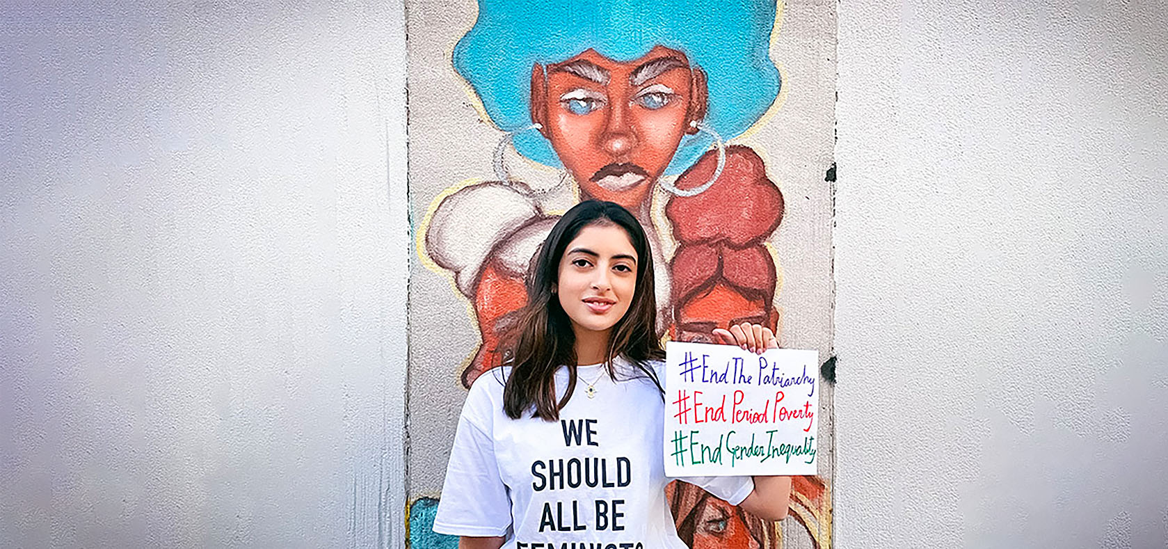 Nanda shows her messages outside Fashion Institute of Technology In New York City, on 3 April 2021. Behind her is a student-painted mural on the theme of Black Lives Matter, with a focus on empowering black women. Photo: Courtesy of Gauri Kanade