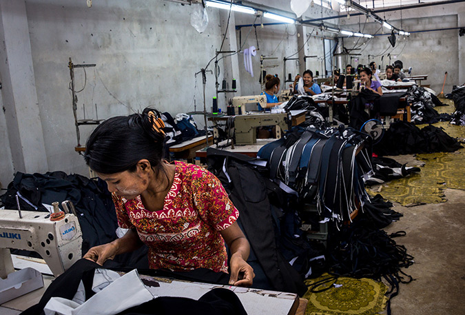 Burmese migrant workers sew clothes in a factory in Thailand's western province of Mae Sot. Their working day runs from 7 am until 8 pm, including overtime, for which they earn less than 200 baht (6 dollars), well below the legal minimum wage of 305 baht. Their monthly income barely covers rent and food, leaving little opportunity for saving and reducing them to living day-to-day. Photo: UN Women/Piyavit Thongsa-Ard