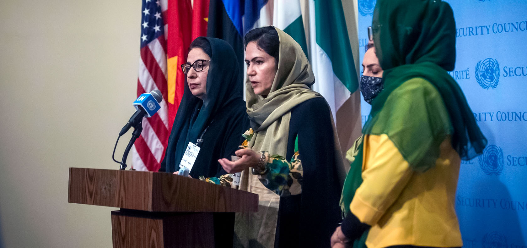 4 Afghan females are standing and speaking at the podium