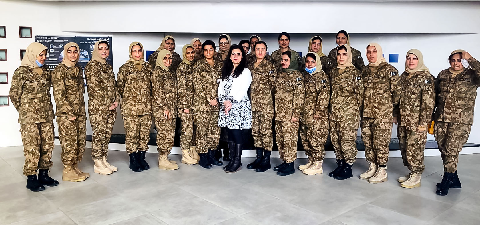 A group of female solders standing with their female civilian instructor for a group-photo after the training session was done.