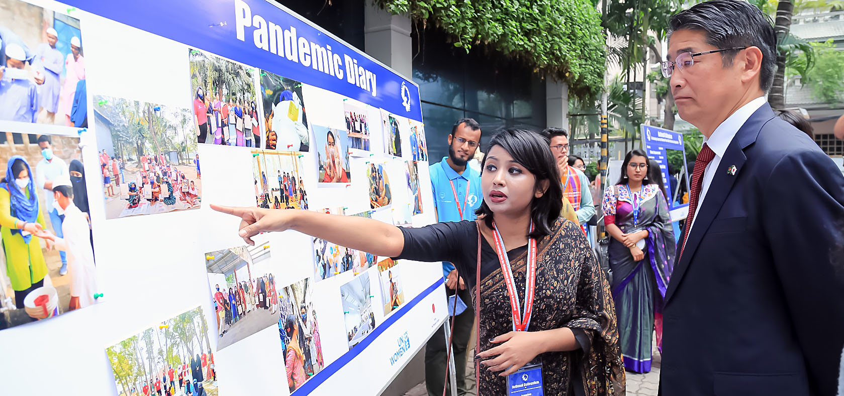 Young Bengali woman is presenting some information on the photo board to a Japanese male ambassador