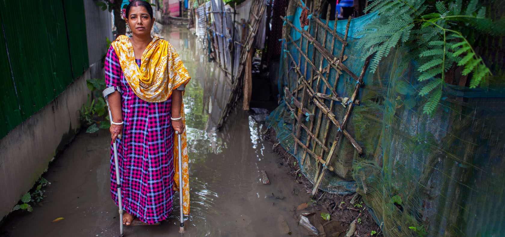 A Bengali woman standing on a path way with her supporting walkers.