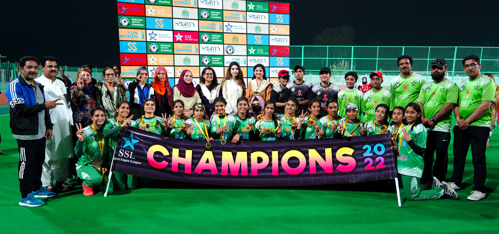The winning team, from Lahore city, poses at the 12 March 2022 hockey tournament in Sukkur city, Pakistan. Also shown are the tournament organizers, UN Women Team and Soorty Enterprises. Photo: UN Women/Hassan Ali Abbasi