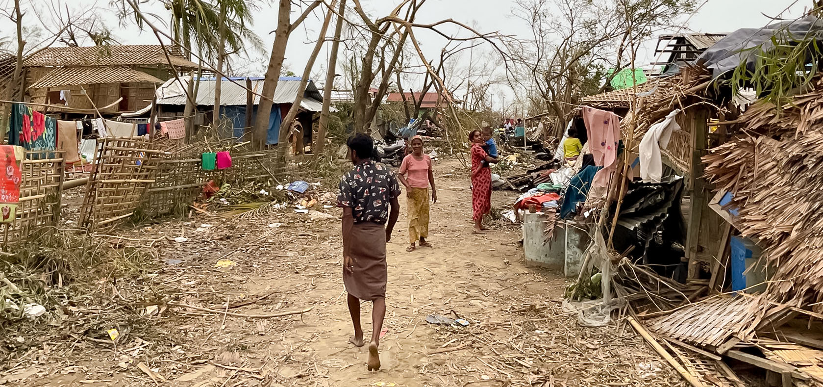 Internally displaced people walk in Camp Maw Ti Ngar, destroyed by Cyclone Mocha. Sittwe, Rakhine. Photo: UNOCHA/Pierre Lurioux