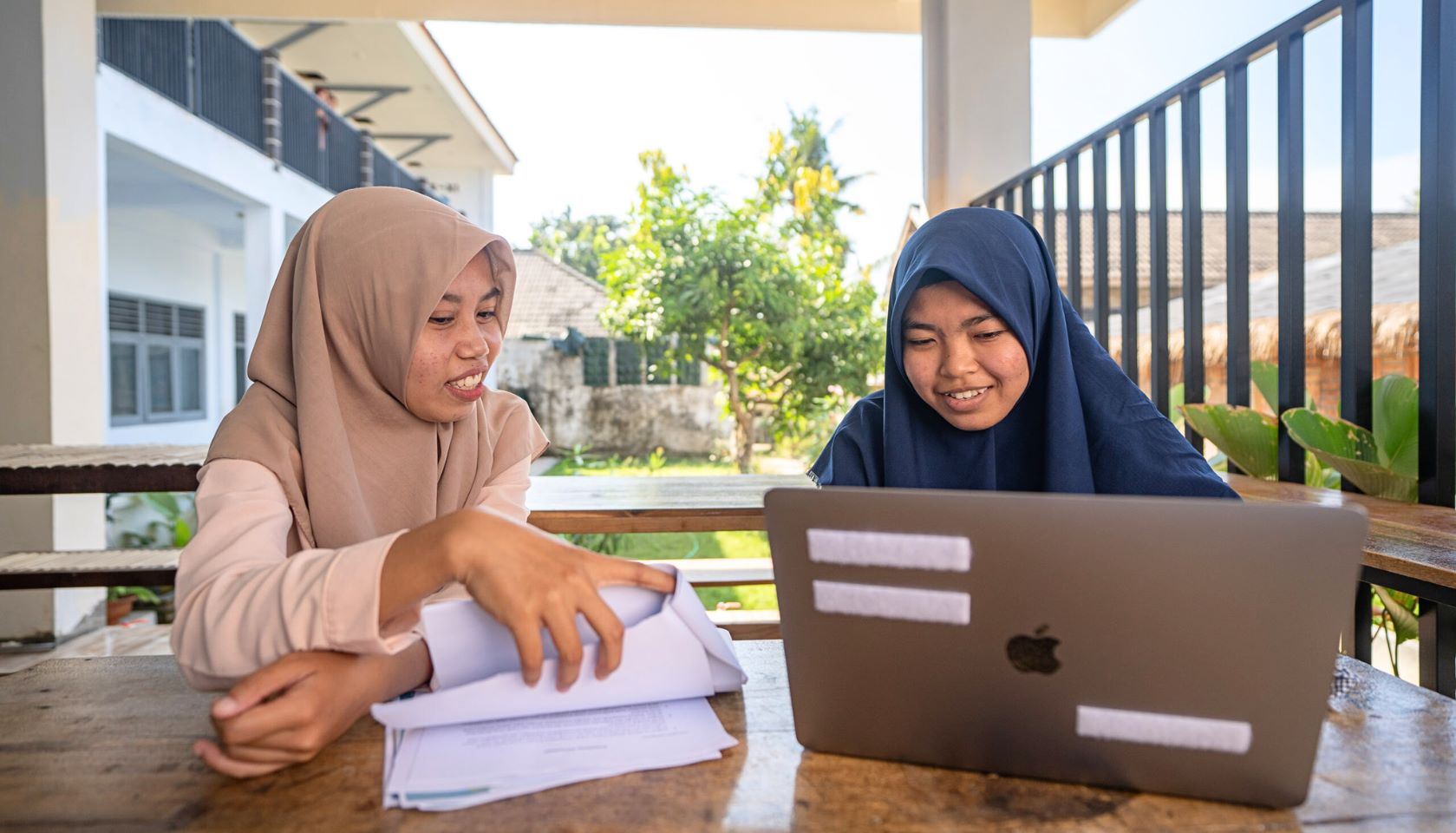 Two young women use a laptop for learning in Guluk-Guluk in East Java Province, Indonesia.