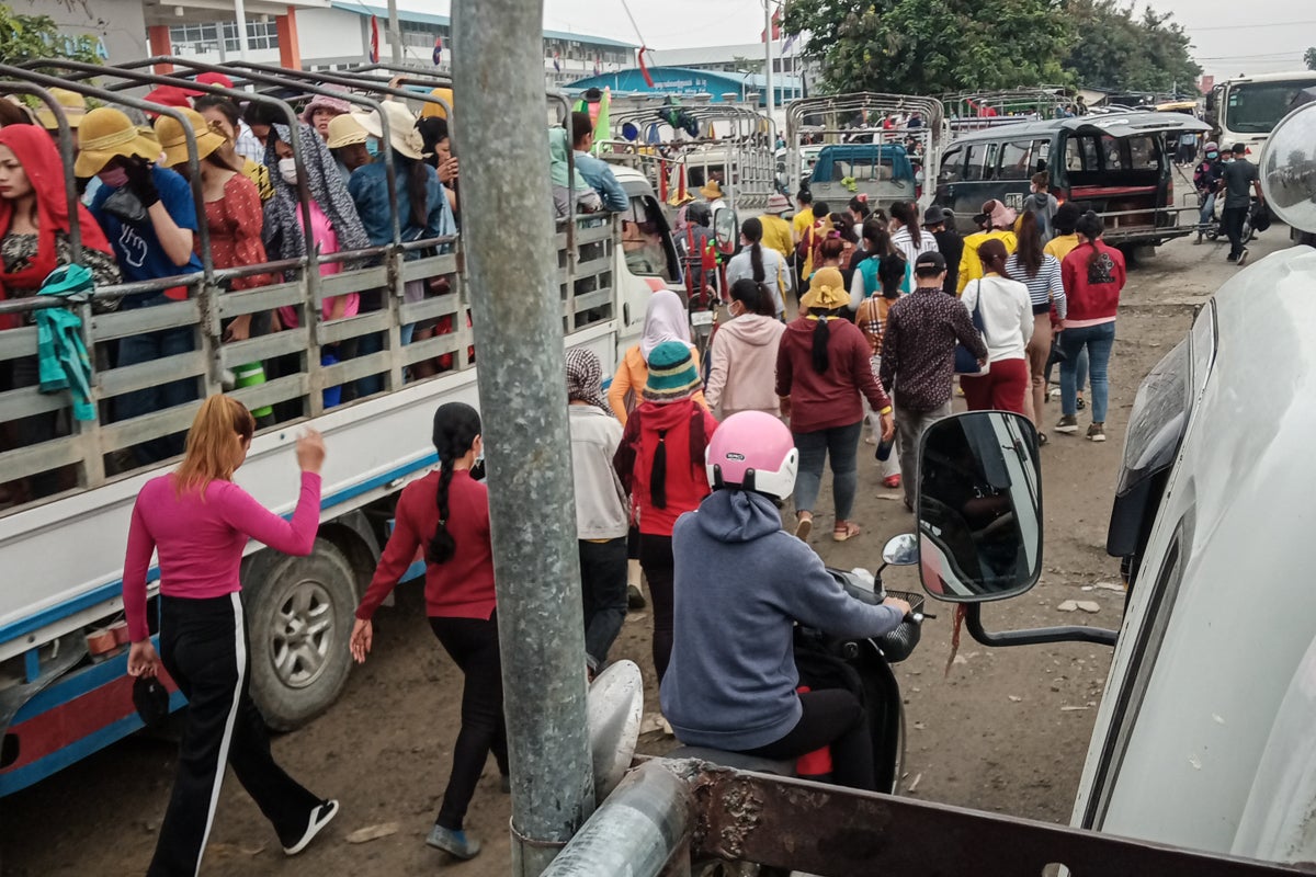 Workers walking down a busy road full of cars. 