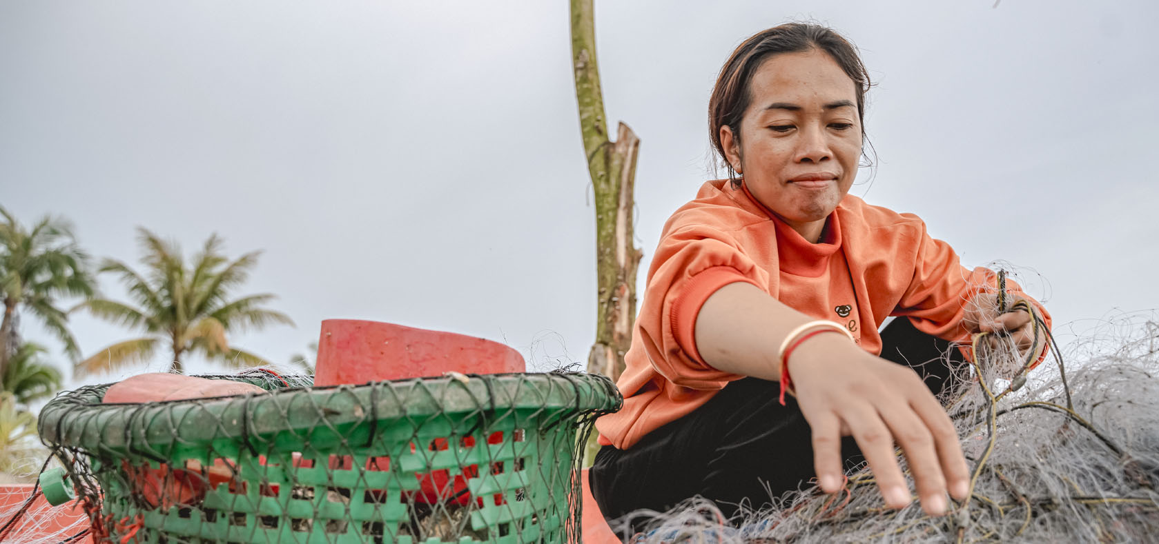 Perl Seanglay collects fishing line at Nesat Village Village, Chrouy Svay Commune. Photo: UN Women/Ploy Phutpheng