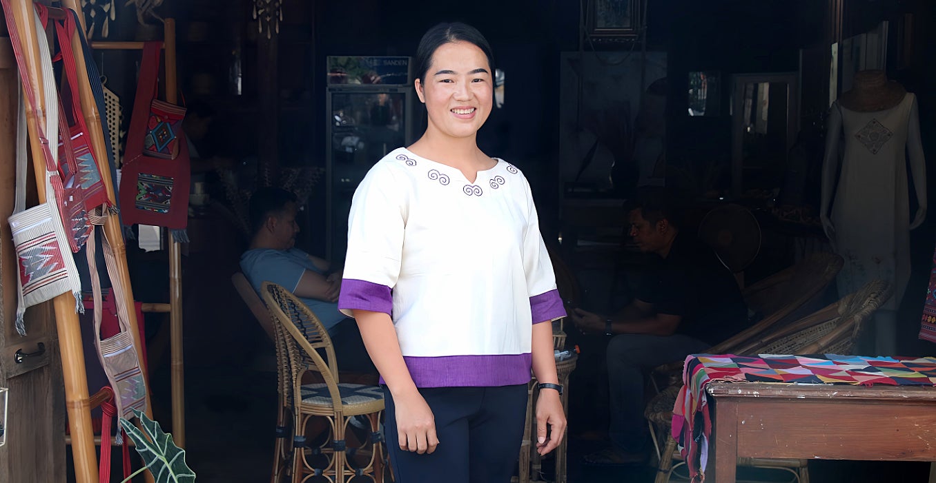 Hua Sae-Wue wears a shirt she made and poses in front of the WEE Centre in Chiang Kong District. 