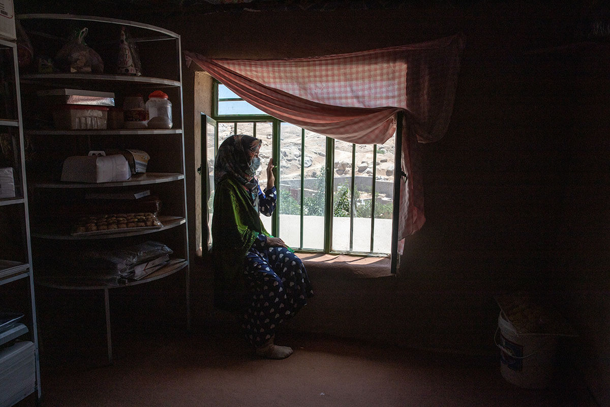 A 31-year-old woman sits by the window. She used to be an entrepreneur before the Taliban takeover. Photo: UN Women/Sayed Habib Bidell.