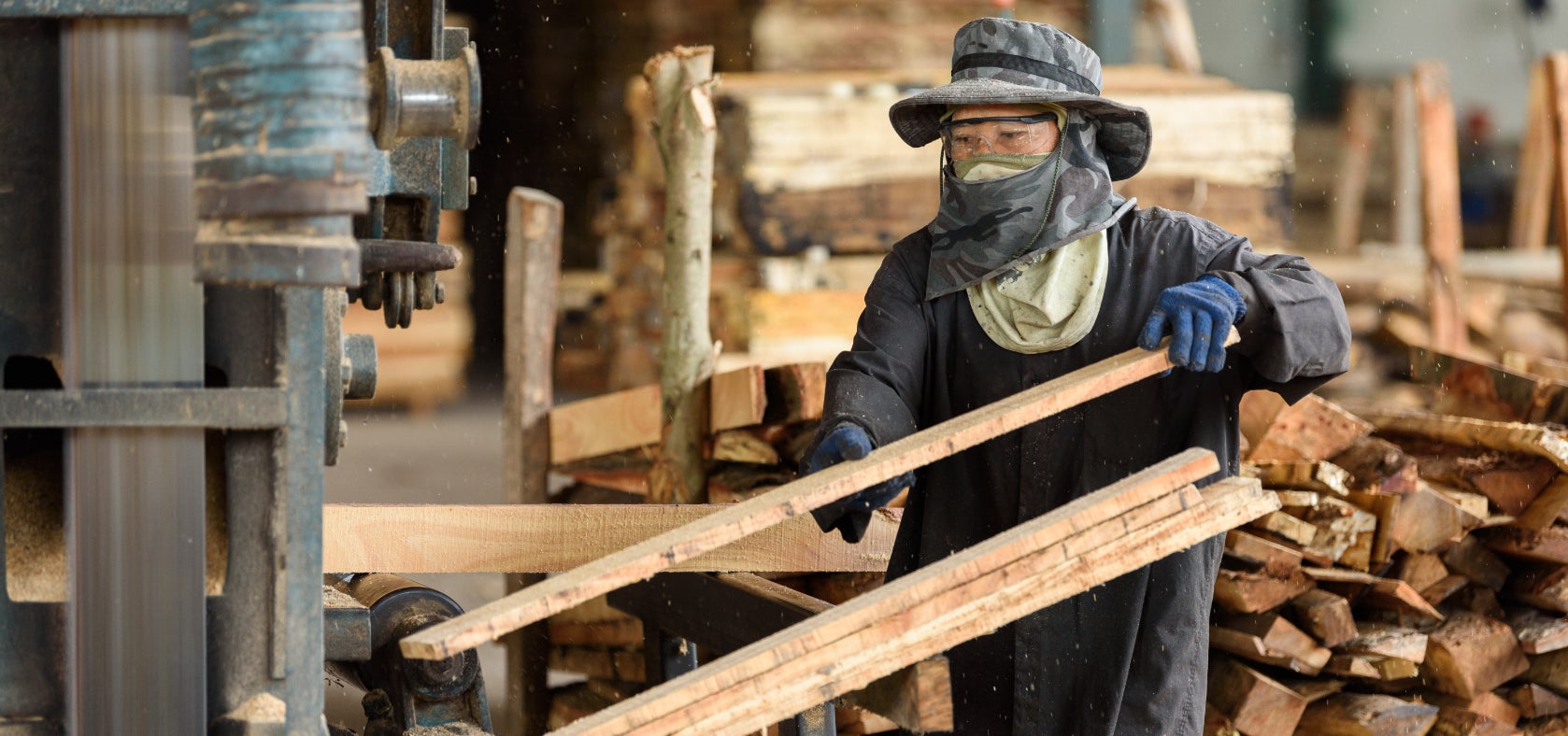 A worker handles timber in a sawmill.