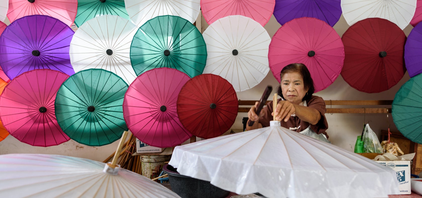 A woman works on a parasol in Chiang Mai, northern Thailand. Women migrant workers earn significantly less than both Thai men and women, and also often send their savings in the form of remittances to their families at home. 