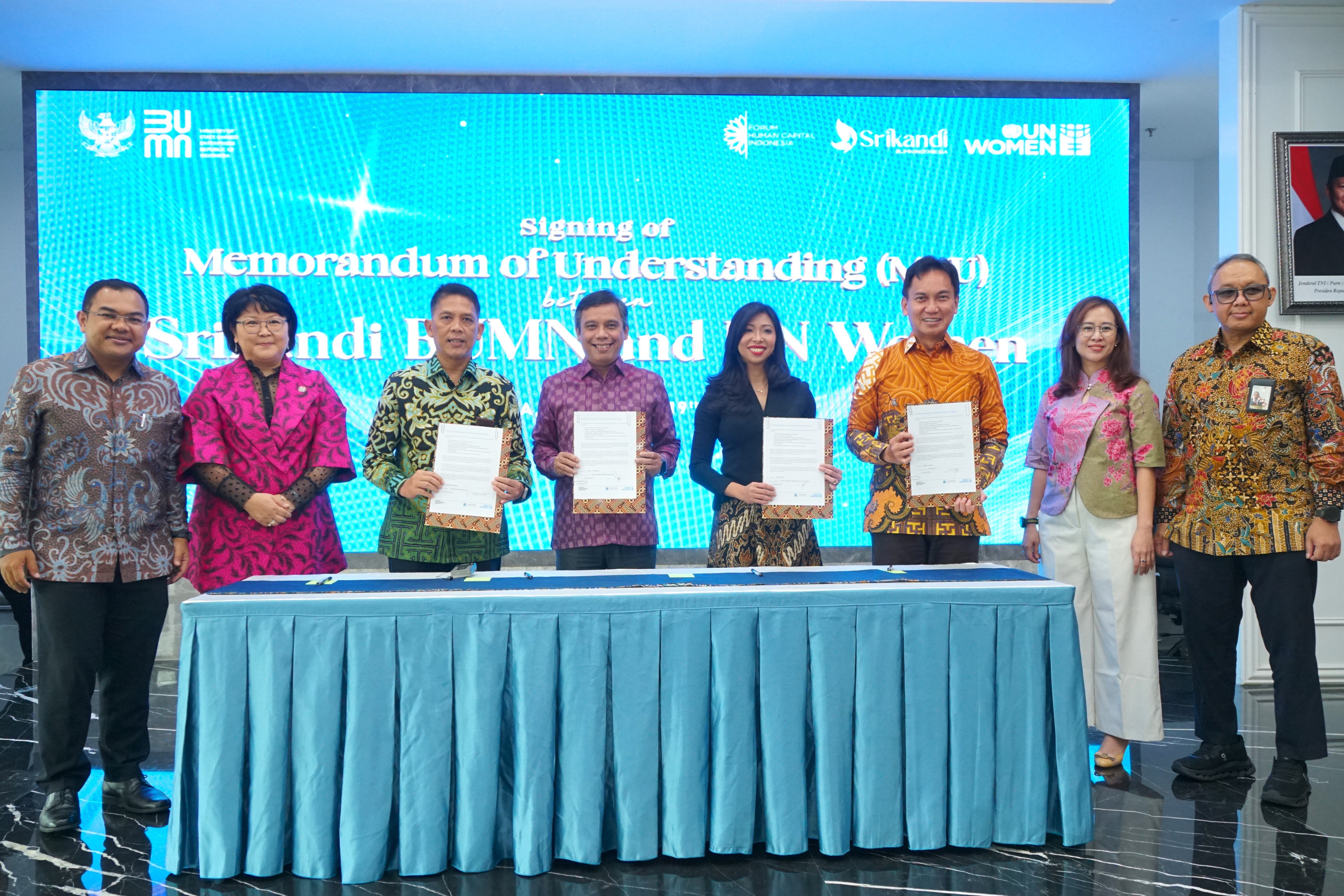 Eight people standing behind a desk. Four people in the middle held a signed Memorandum of Understanding