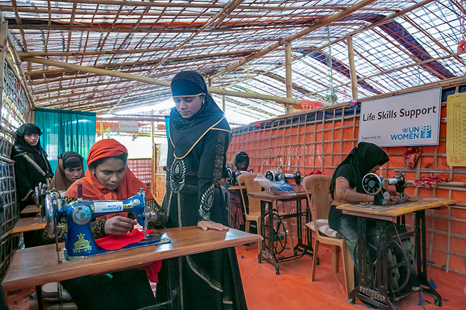 After eight days of training, Somjida, 15 (standing), completed her first clothing item, a red blouse, at the UN Women-supported Action Aid Women Friendly Space in Balukhali Rohingya Refugee camp. Photo: UN Women/Allison Joyce