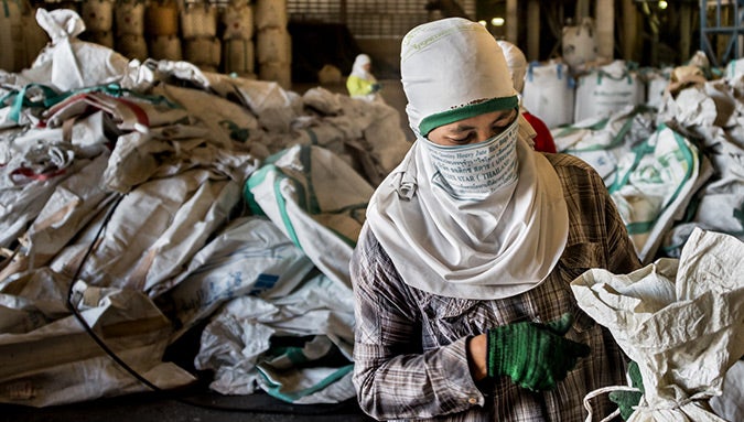 A Burmese worker handles empty sacks at a rice mill in Ubon Ratchathani province. The sacks are returned  at a rate of several hundred per day to the mill, where workers sort, clean and repair them for re-use.  Photo: UN Women/Piyavit Thongsa-Ard