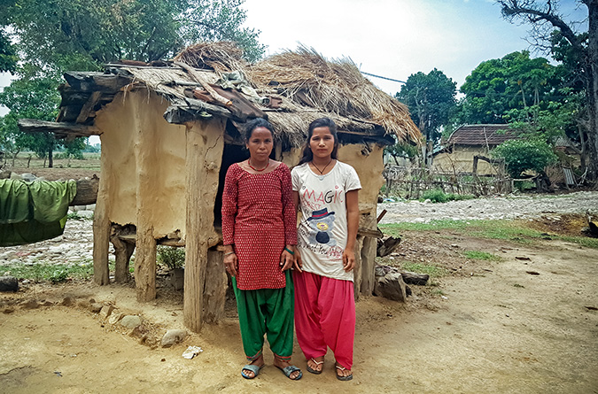 Jayanti, 17 years old and Jamuna, 35 years old outside a chhaupadi hut, a harmful traditional practice, that Jamuna used for 22 years and was used by Jayanti for 5 years. Through advocacy from Restless Development Nepal, the mother and daughter have not slept in the hut for over a year and the shed will soon be demolished. Photo: UN Women/Nuntana Tangwinit