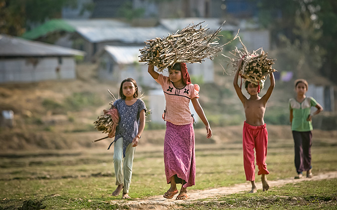 Girls carry firewood in Balukhali camp March 5, 2018 in Cox's Bazar, Bangladesh. Photo: UN Women/Allison Joyce