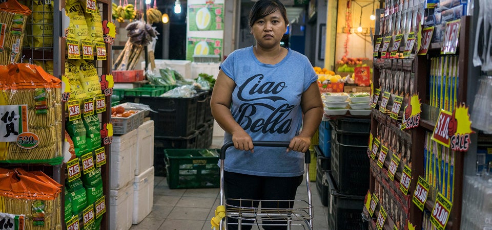 Nurachayatun Siti, a 35-year-old Indonesian domestic worker from Surabaya Java, does the family shopping early Saturday morning in Sembawang Hills Estates, Singapore. This is Nur's second job as a domestic worker in Singapore. The first when she was 19, was a painful and demoralizing situation where her employers had her sleep on the floor for two years, with little food, no time off, earning only S$20 per month. The rest of her wages were either withheld or taken by the agency that placed her. When her employer accused her of theft, she gladly left. This time she has returned on her own terms earning well about the average S$550. On her one weekly day off, Nur learns how to sew, meets with friends, and attends labour law discussions to better protect herself. Photo: UN Women/Staton Winter