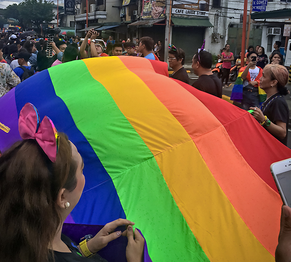 A group of marchers walk with a giant rainbow flag at the 29 June Pride march in Manila. Photo: UN Women/Rebecca Singleton