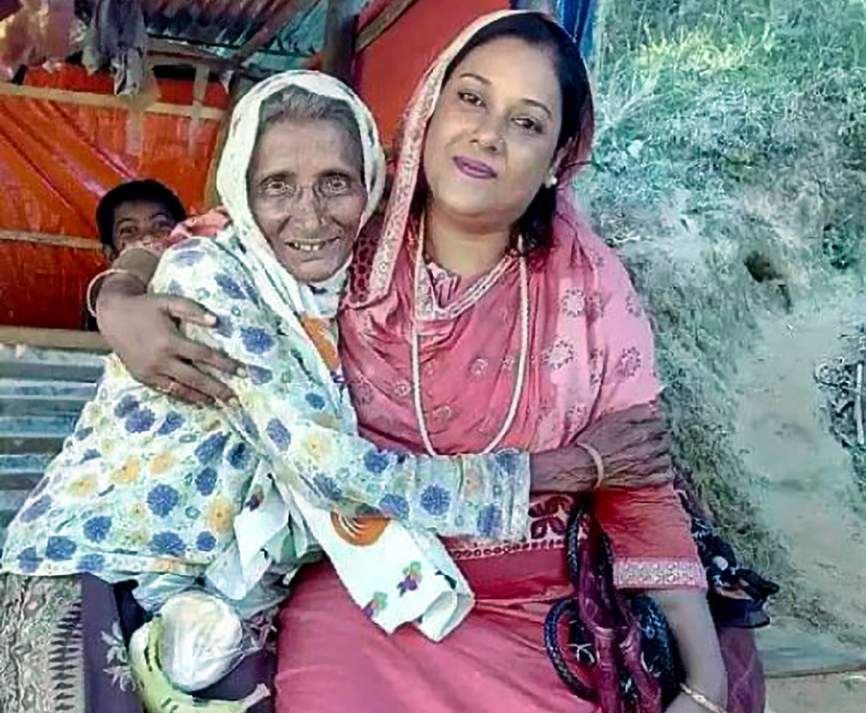 Photo of Neelima Akter Chowdhury sitting with an old lady. Photo courtesy of Neelima Akter Chowdhury