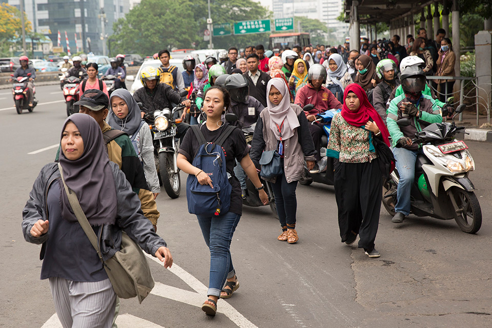Photo of more than a hundred of indonesian women walking through the intersection of a main road in Indonesia. Photo: UN Women/Ryan Brown