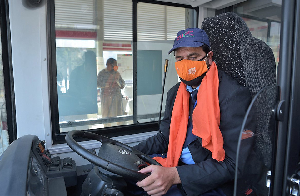 Driver of BRT bus in Peshawar wears orange mask and scarf to show solidarity with 16 Days of Activism against GBV. Photo: UN Women/Habib Asgher