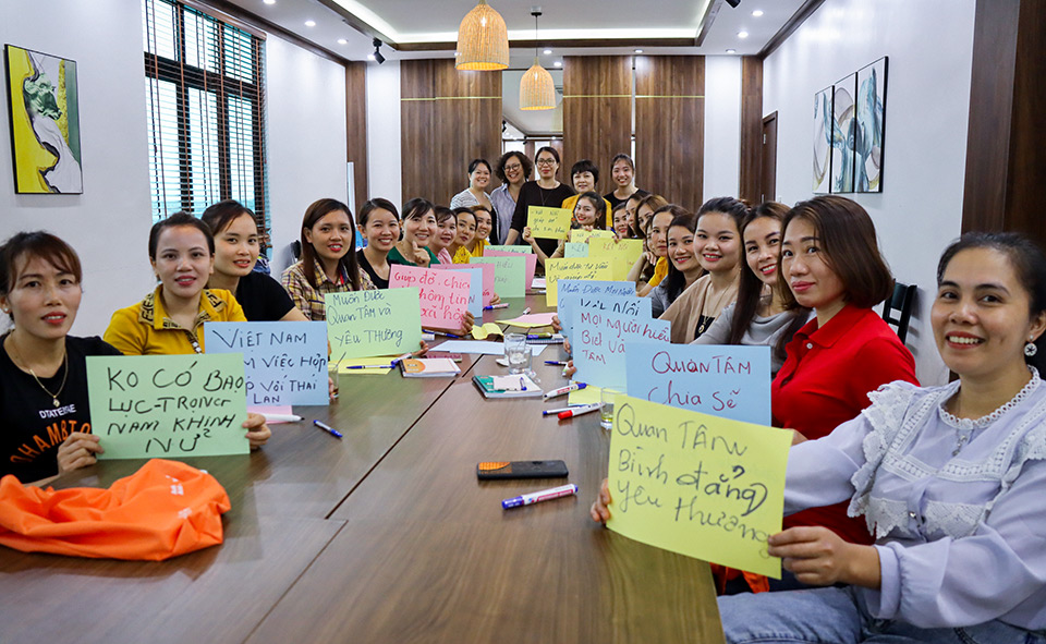 Migrant workers attending the UN-supported workshop in Ha Tinh, Viet Nam, on 23 April 2021 show their hopes for future journeys abroad. The sign at the left foreground says, “No violence-No valuing men above women”. Photo: UN Women/Thao Hoang