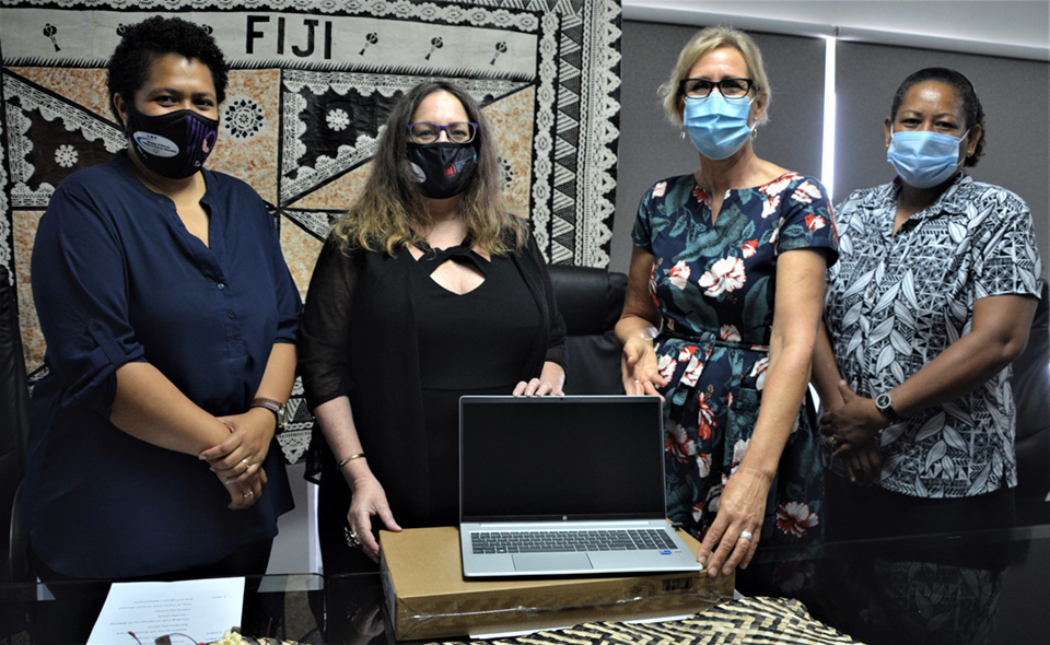 Permanent Secretary of the Fiji Ministry of Women, Children and Poverty Alleviation, Jennifer Poole (second from left) with Ministry staff, receives ICT resources from UN Women Fiji Multi-Country Office Representative, Sandra Bernklau (third from left). 