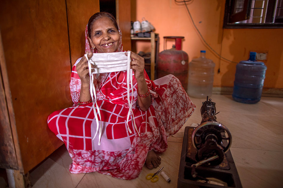 Laxmi Devi, 55, shows a mask she has made. She is using the sewing machine that she bought with a loan received through SEWA to make and sell masks in New Ashok Nagar neighbourhood of New Delhi. Her mindset about women and work has changed. When she was younger, women didn’t work, but she says now are different. “Girls should go out and work now. Boys and girls are equal,” she says. Photo: UN Women/Prashanth VIshwanathan