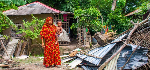 Saleha Begum, 45, in Patarkhola village of Ramzan Nagar union at Shyamnagar upazila in Satkhira, stands near some of the remaining damage after the roof of her home was torn off by Cyclone Amphan in 2020. She received cash support from UN Women following the cyclone, which compounded the hardships already wrought by the COVID-19 pandemic. Photo: UN Women/Fahad Kaizer